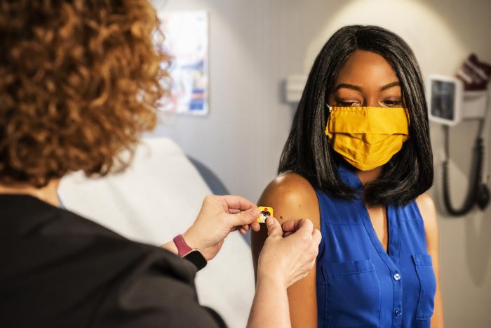 a woman gets a bandaid after receiving a vaccine to her arm 