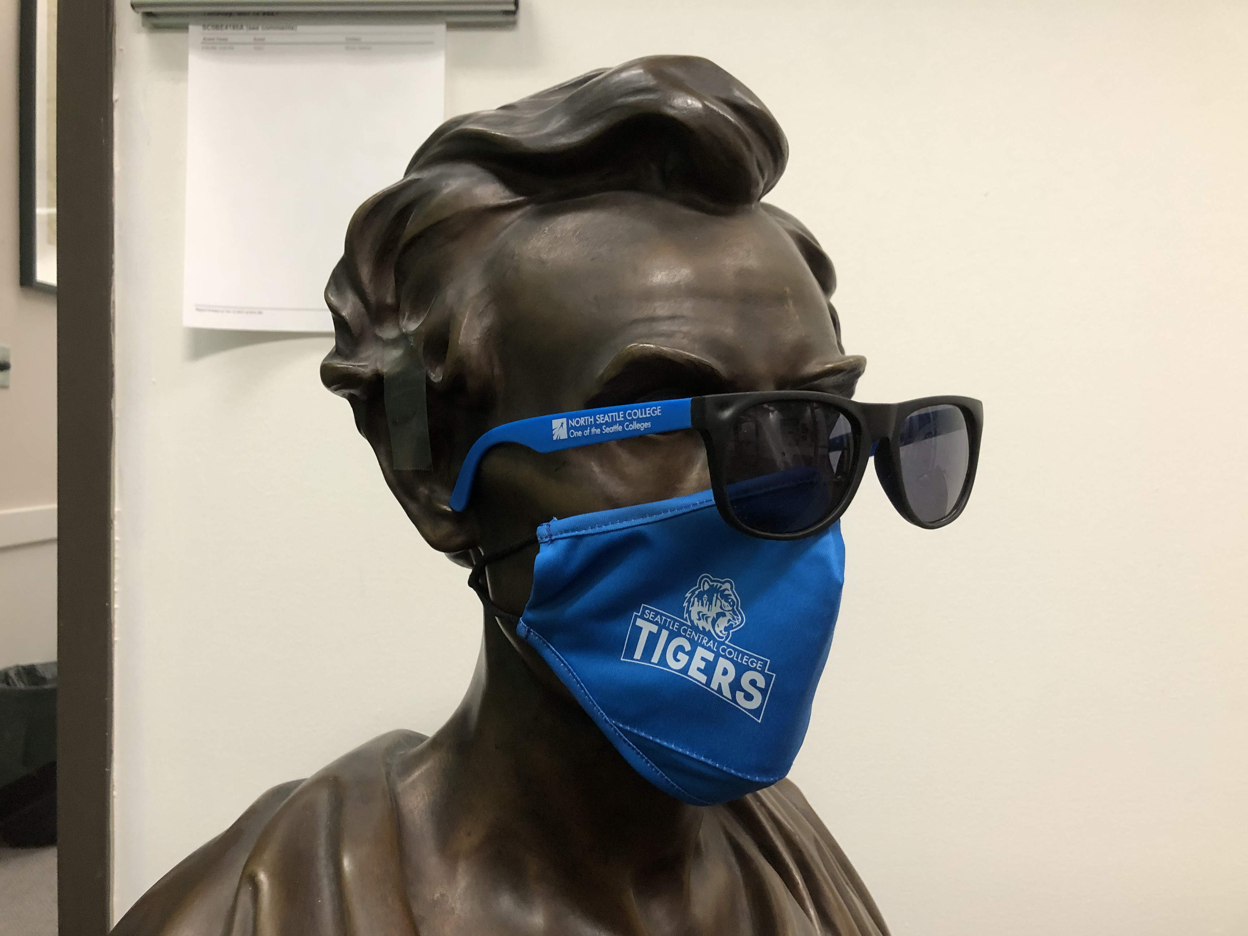 a bust sculpture with glasses and a Seattle Central face mask 
