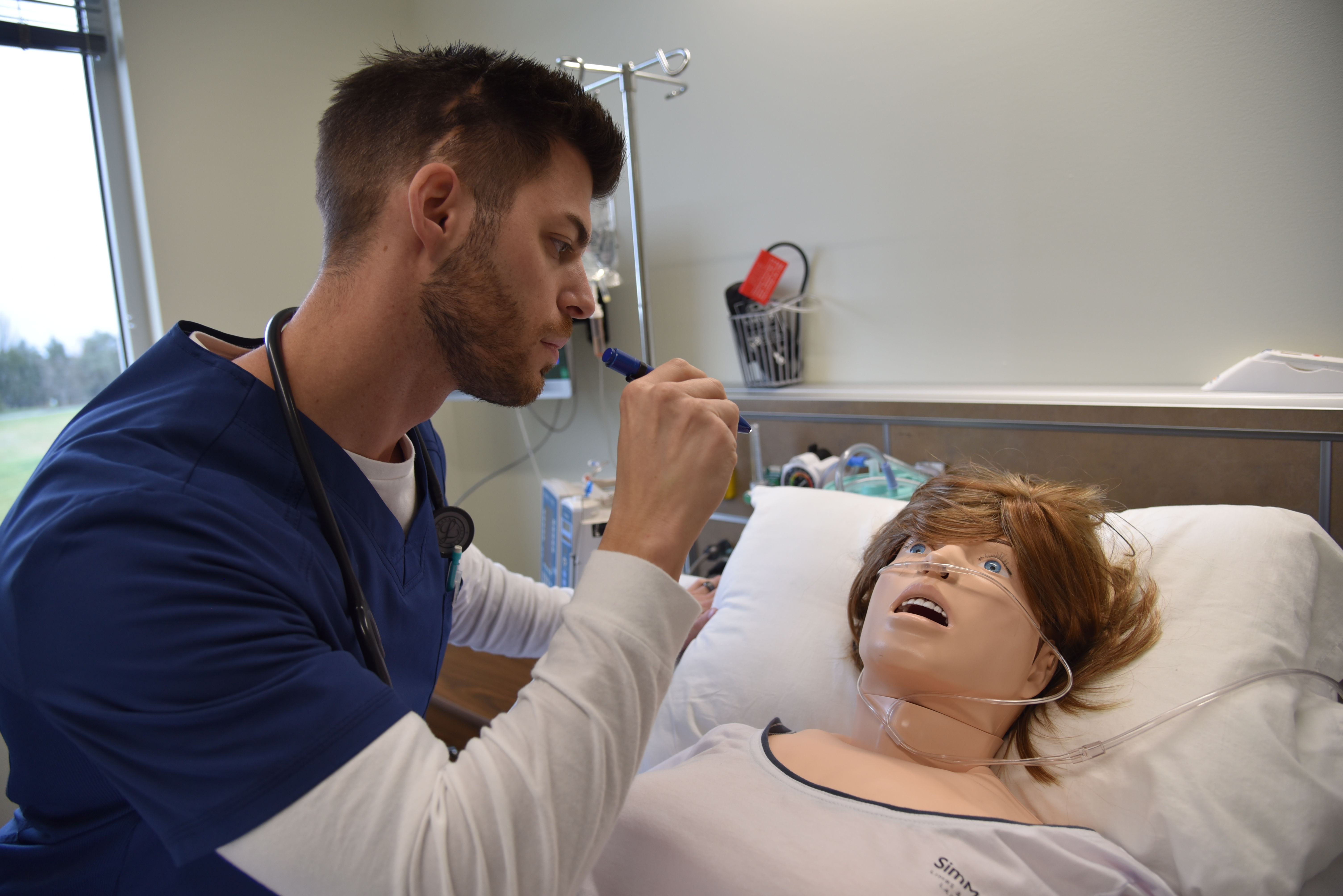 a nursing student trains with a patient simulator