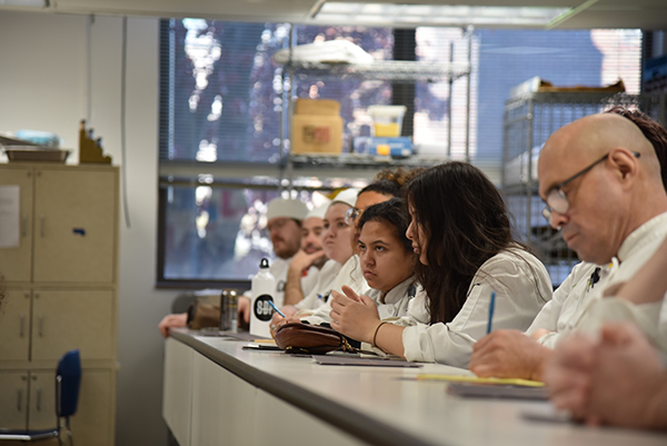 A student pays close attention to a culinary lessonb