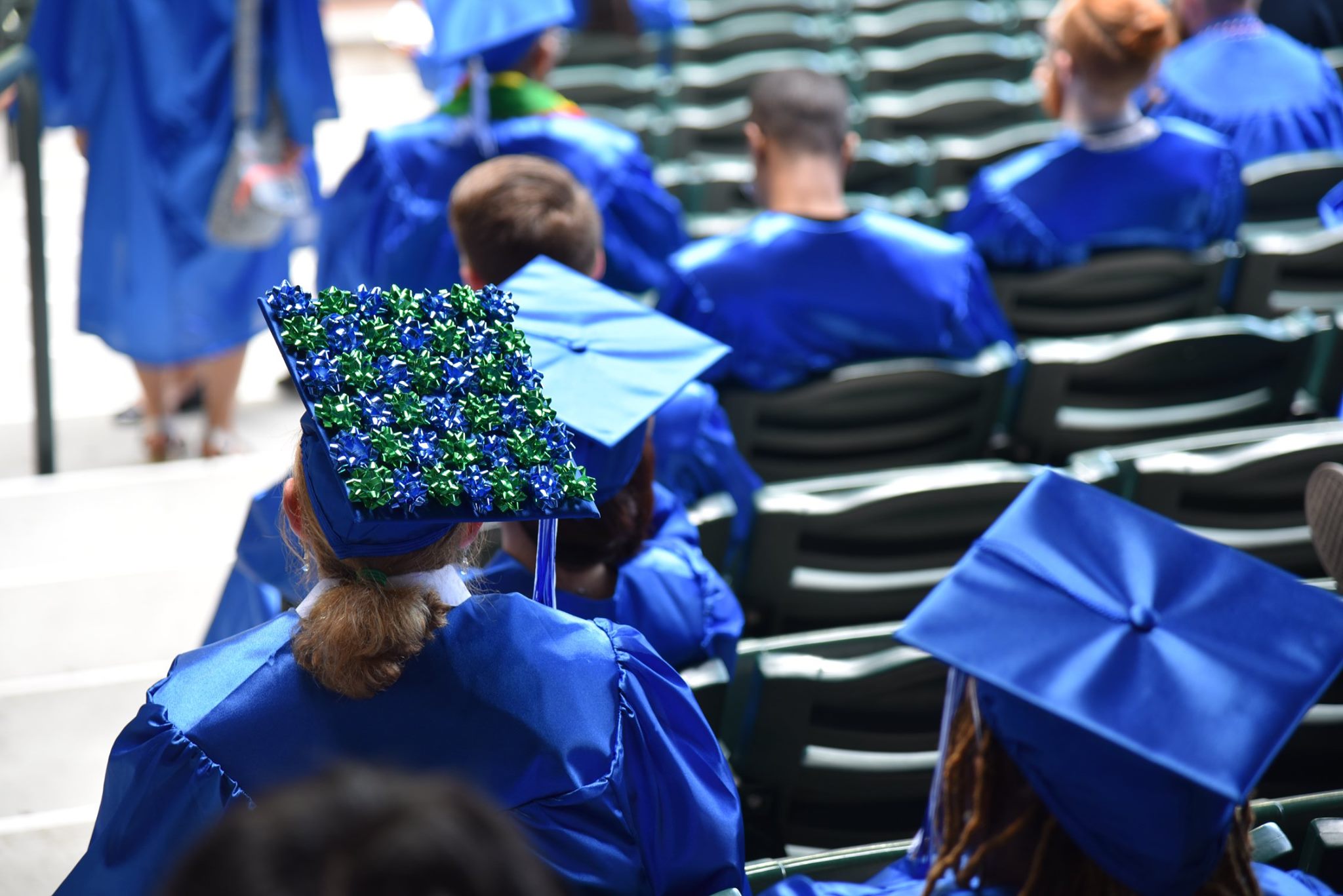 two students wait for the commencement ceremony in the stands of the ball field