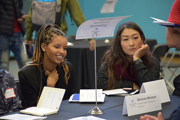 two female students smile while talking to a networking volunteer